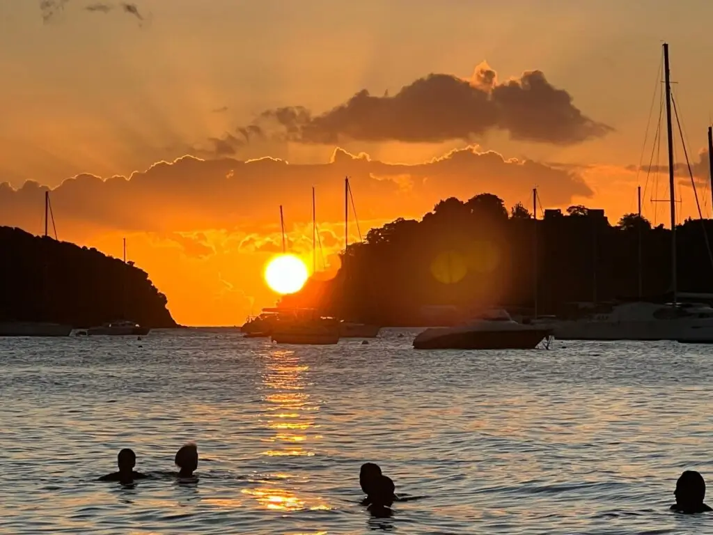 Galerie photos Martinique - Coucher de soleil sur une plage en Martinique avec baigneurs et voiliers au mouillage.