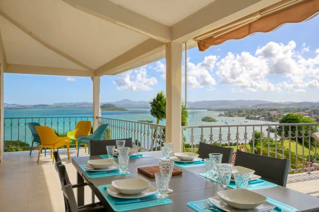 Terrasse spacieuse avec espace repas et coin détente, offrant une vue imprenable sur la mer, le golf et les Trois Îlets - Villa Thalizia Martinique.