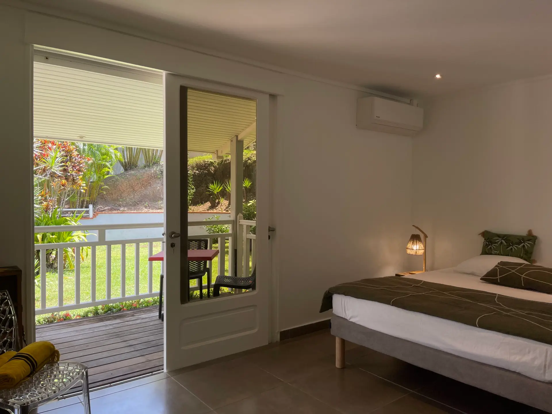 Chambre de la Villa Héliconia en Martinique avec accès direct à une terrasse privative donnant sur un jardin tropical.