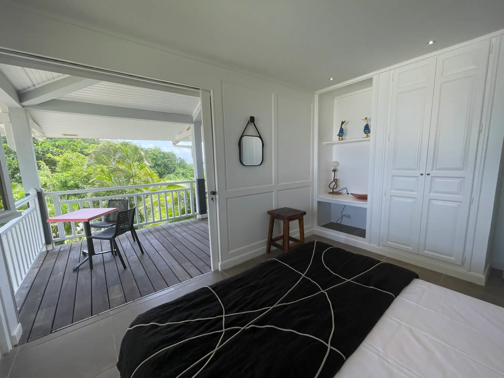 Chambre de la villa Héliconia en Martinique avec accès direct à une terrasse privée donnant sur la végétation tropicale.