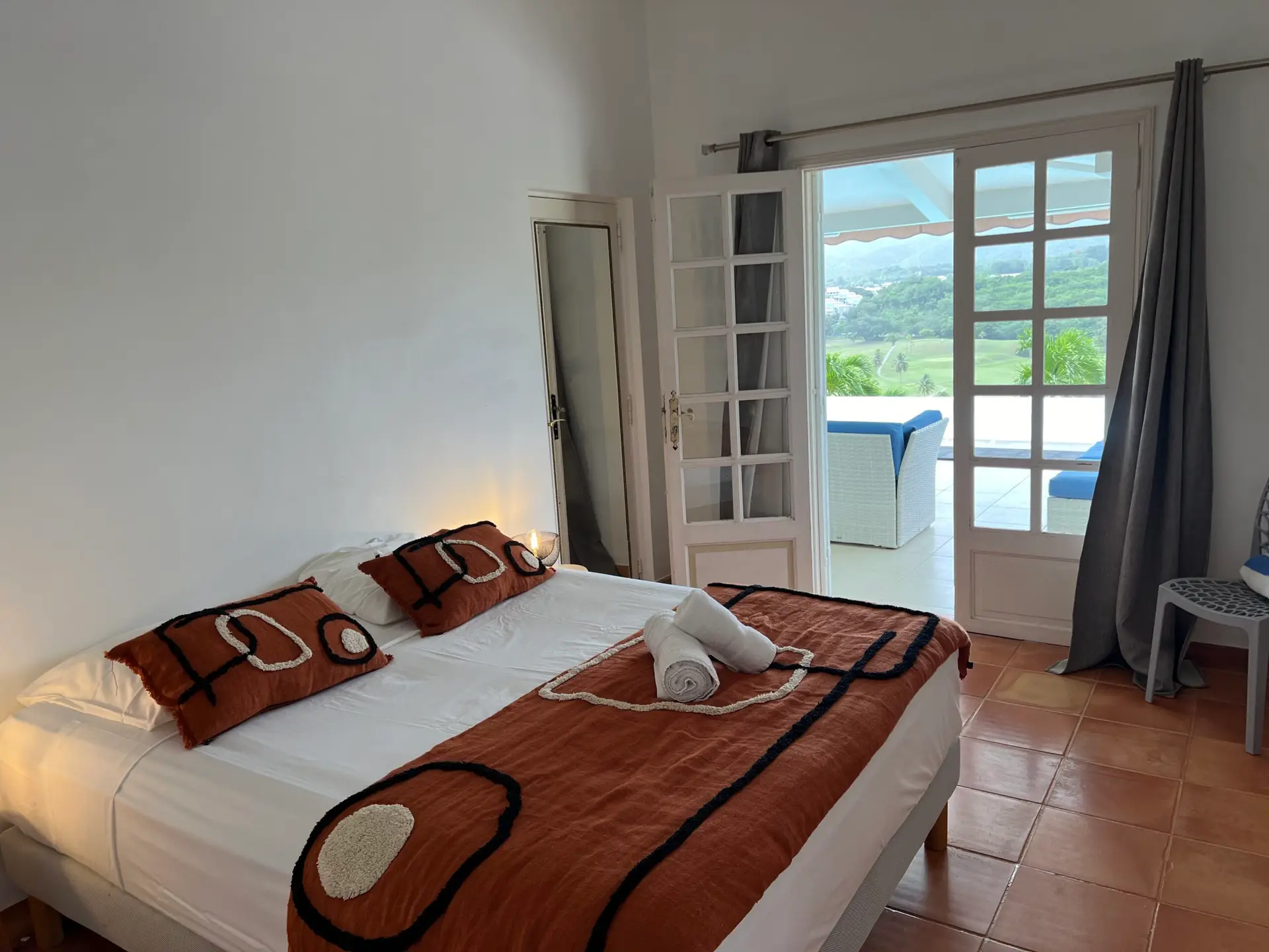 Chambre lumineuse de la Villa Thalizia en Martinique avec accès direct à la terrasse et vue dégagée sur la nature.