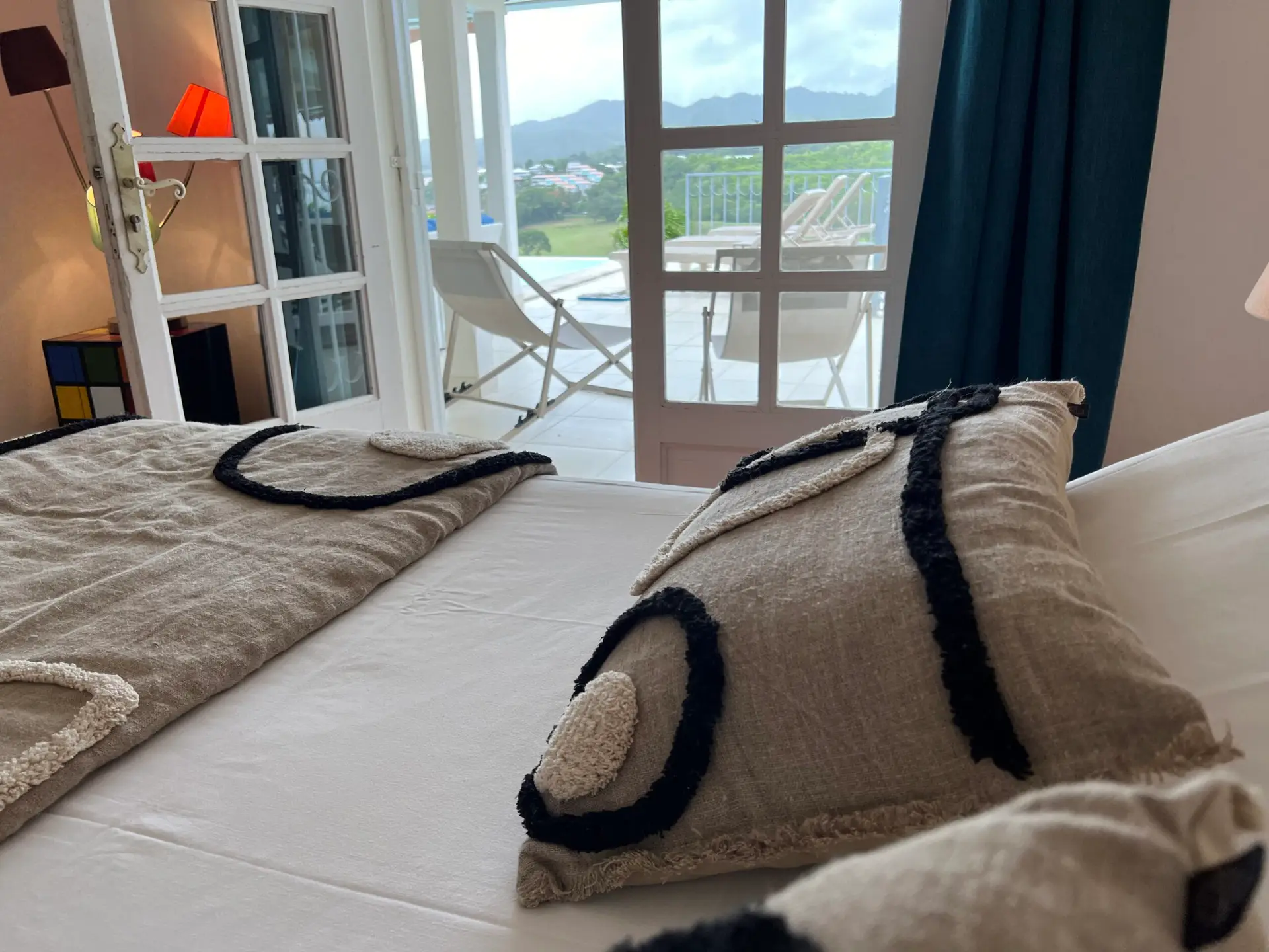 Détail de la chambre de la Villa Thalizia en Martinique, avec vue sur la terrasse et les collines depuis le lit.