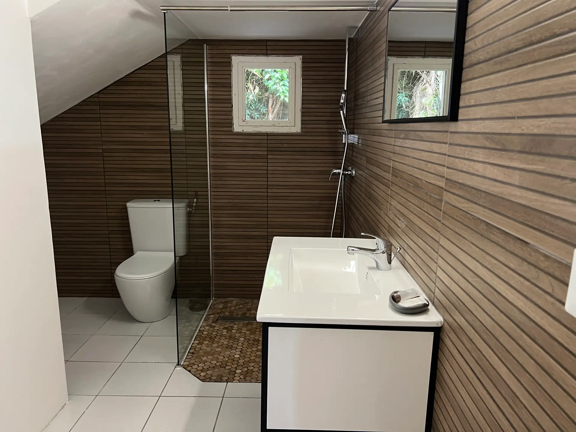 Salle de bain moderne de la Villa Thalizia en Martinique avec douche à l’italienne et revêtement bois.