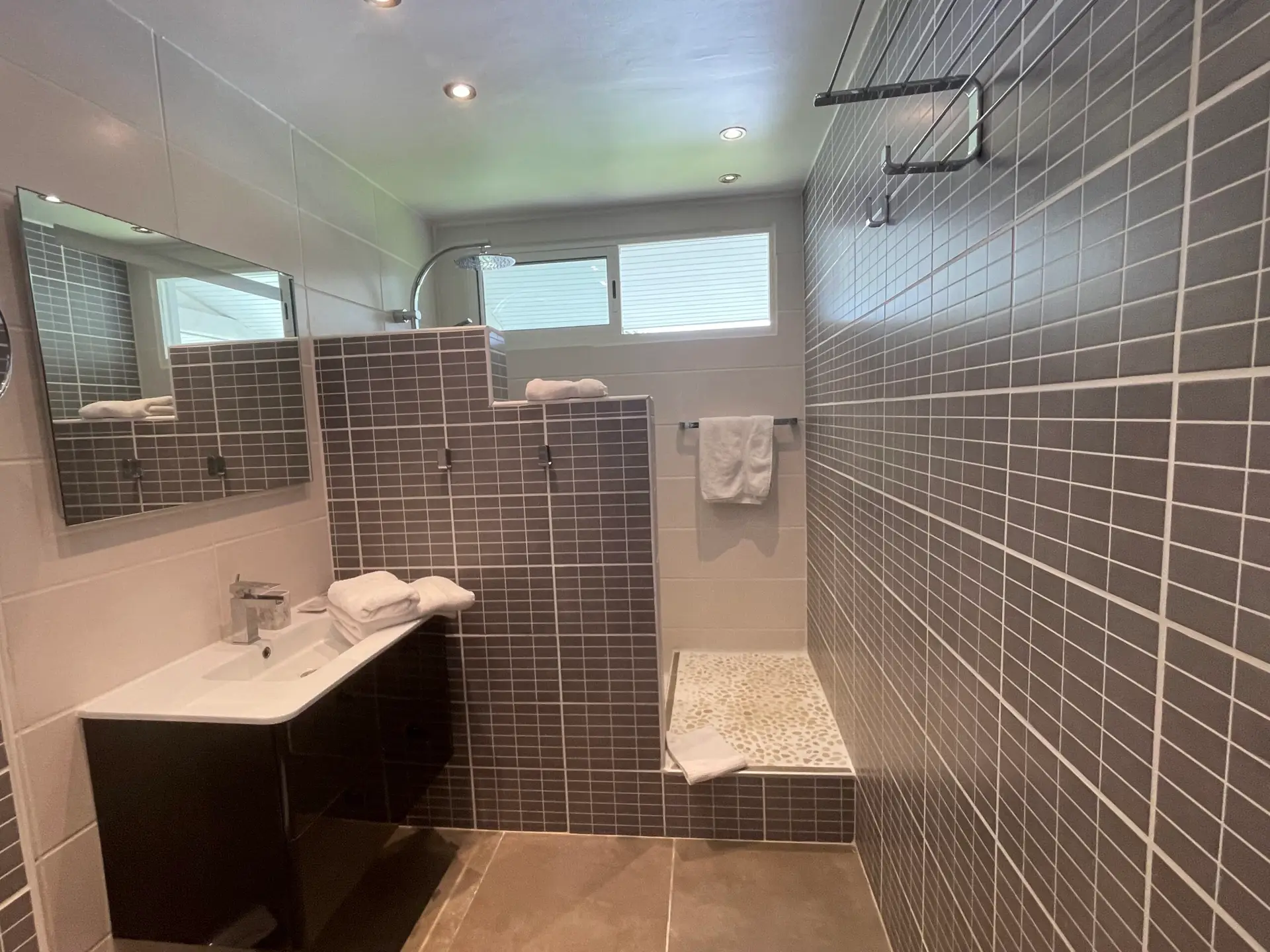 Salle de bain moderne de la Villa Héliconia en Martinique avec douche à l’italienne et double espace de vasque.