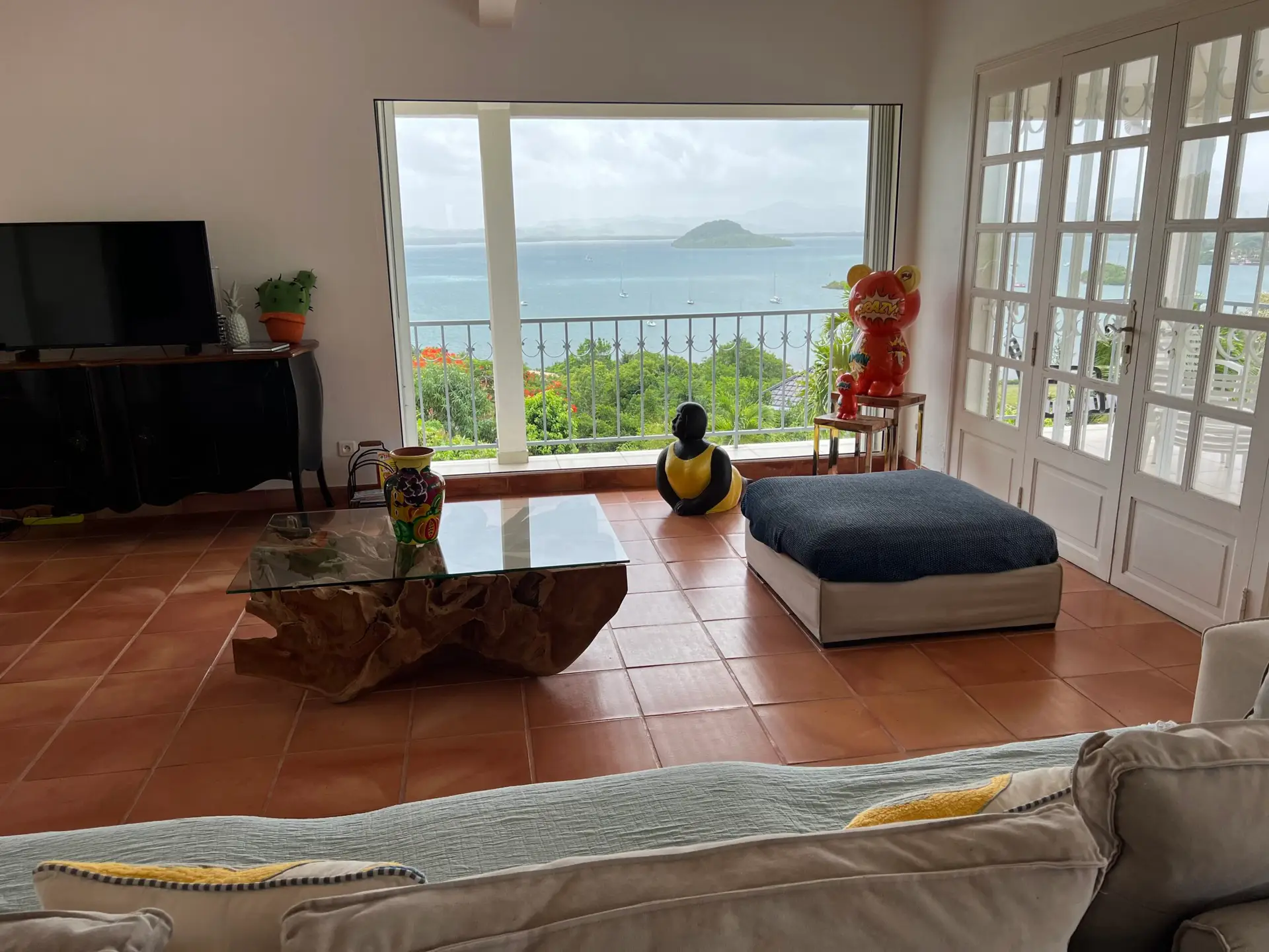 Salon lumineux de la Villa Thalizia en Martinique avec grande baie vitrée offrant une vue panoramique sur la mer et les îlets.