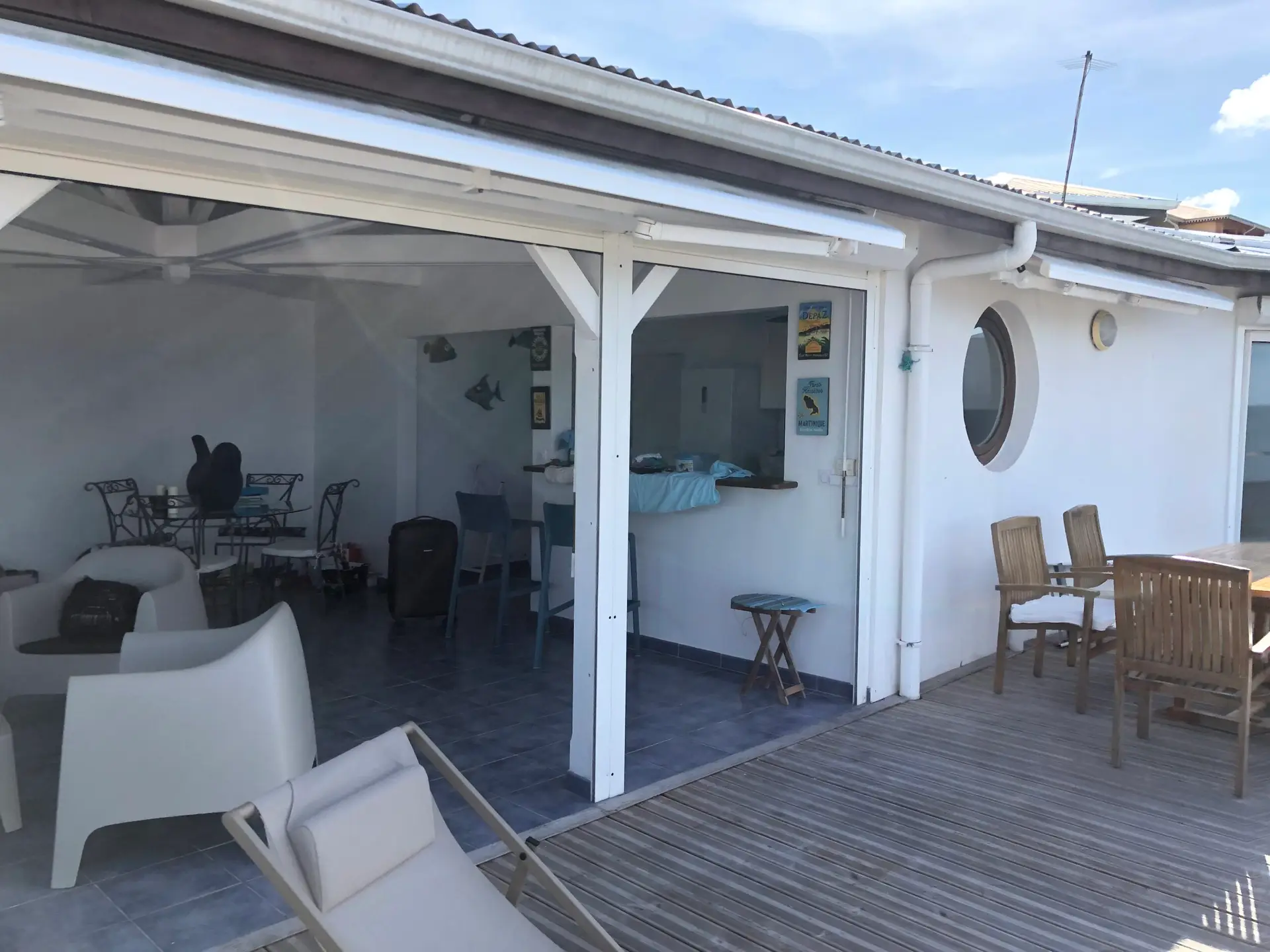 Espace de vie de l’appartement Grand Large en Martinique, ouvert sur une grande terrasse en bois avec coin repas et salon.