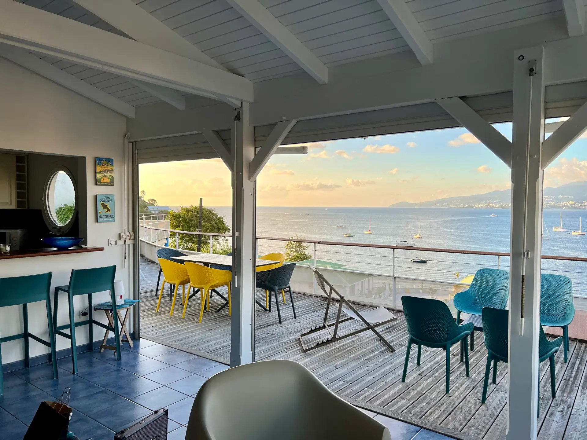 Séjour ouvert de l’appartement Grand Large en Martinique, donnant sur une grande terrasse avec vue panoramique sur la mer et les voiliers.