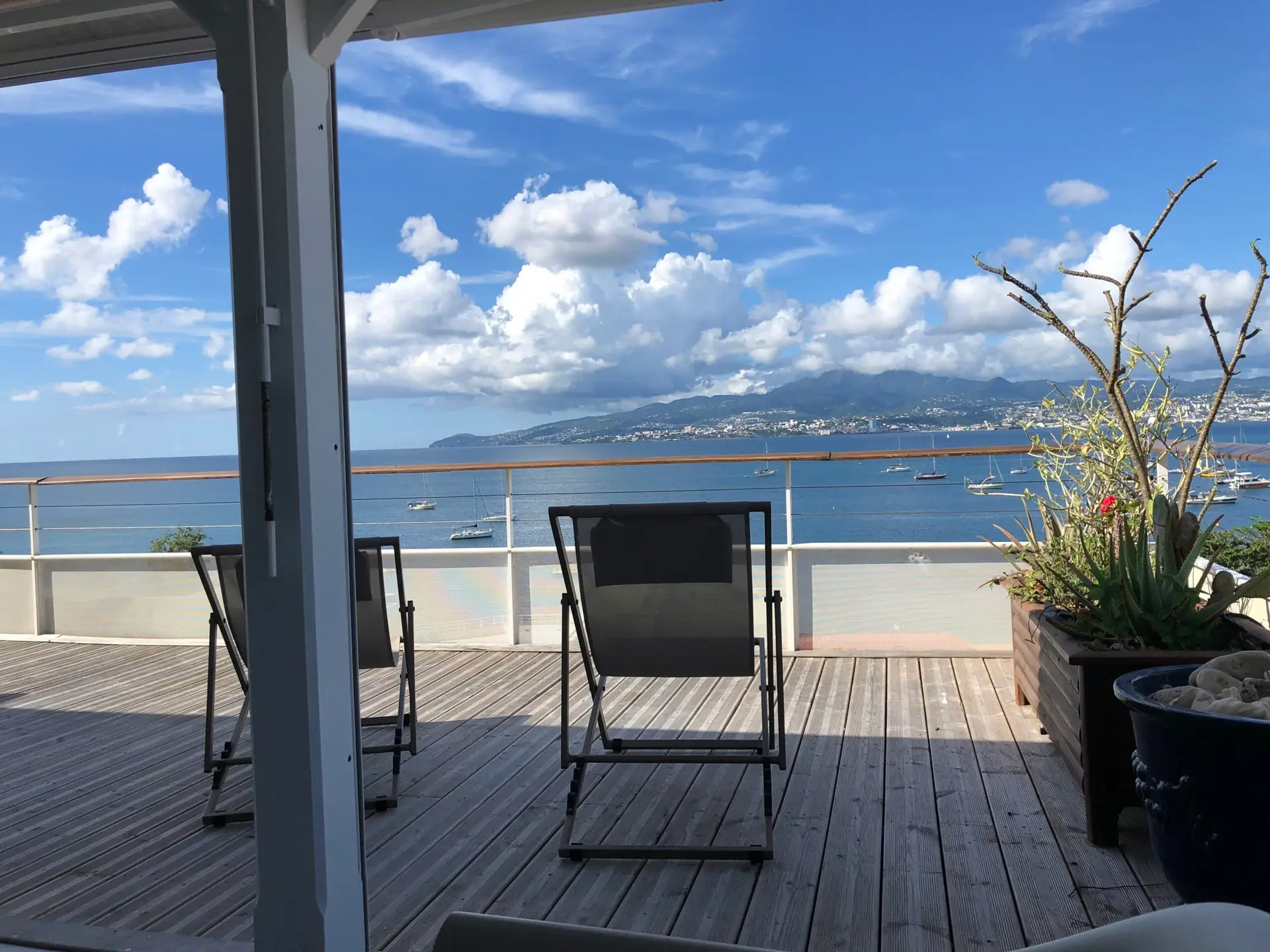 Terrasse de l’appartement Grand Large en Martinique, avec vue panoramique sur la baie, des transats et la mer turquoise.