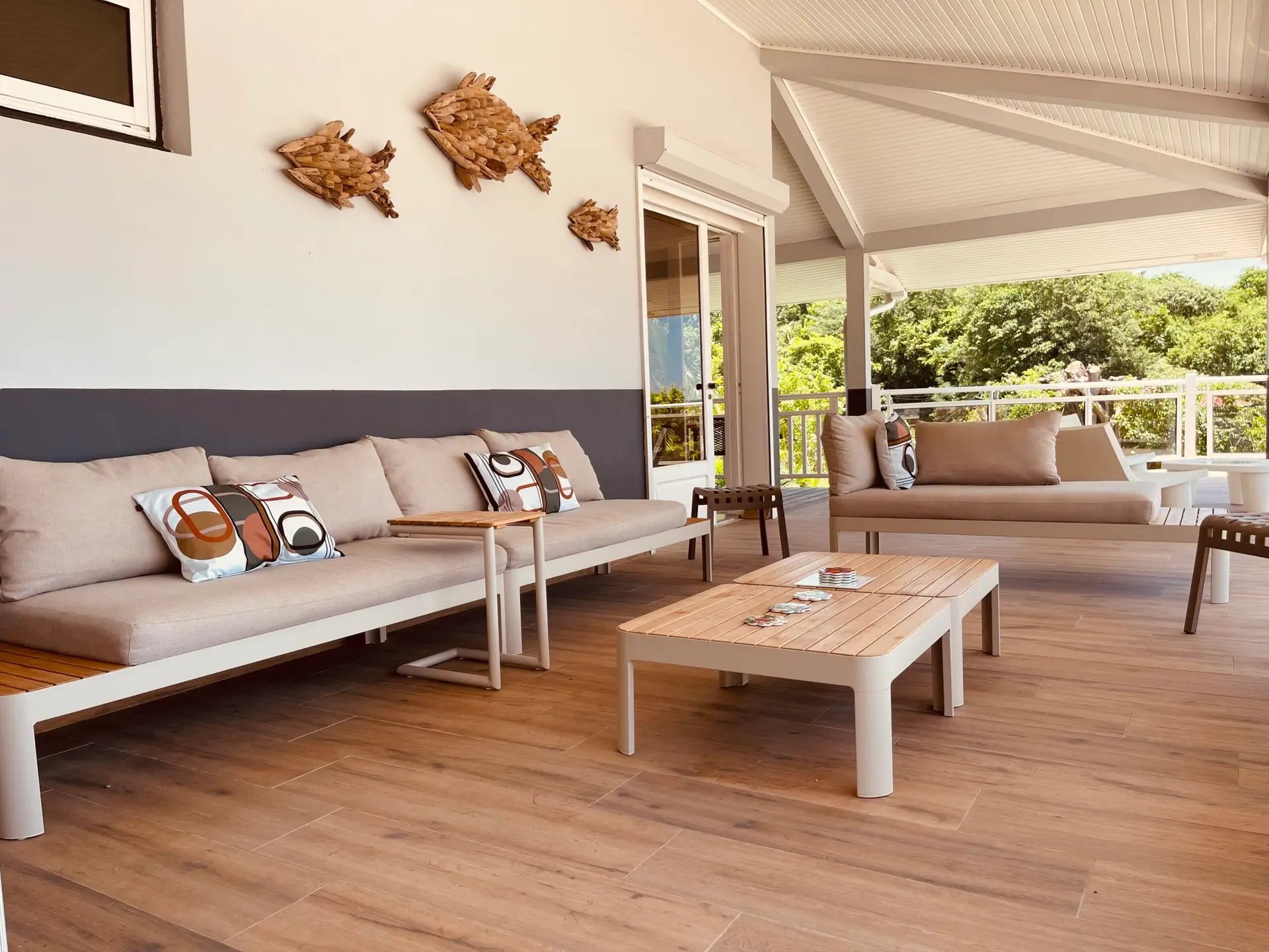 Salon extérieur de la villa Héliconia en Martinique, avec canapés confortables et grande terrasse ouverte sur la nature.